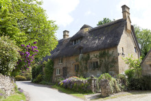 Thatched Roof, Stone Cottage With Flowering Gardens,  By A Country Road, On A Summer Sunny Day .