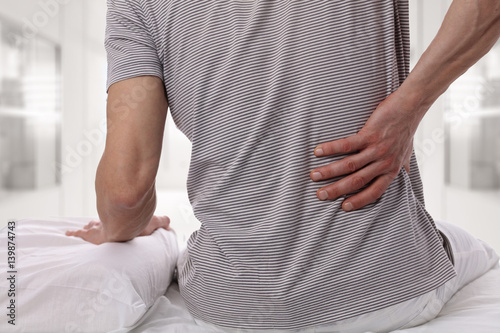 Fotografía Man suffering from back pain at home in the bedroom