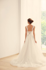 Wall Mural - Bride in a beautiful wedding dress standing near window