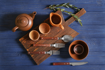 Wall Mural - Set of dishware and cutting board on blue wooden background