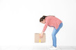 © Africa Studio - Posture concept. Young woman lifting heavy cardboard box against white wall background