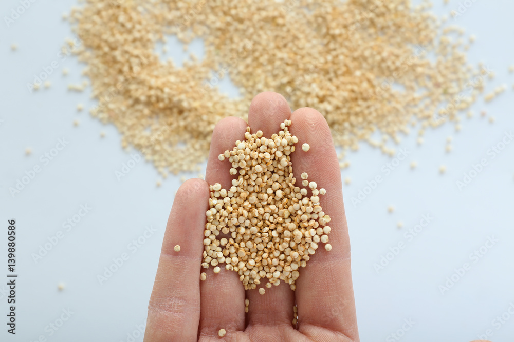 Female hand holding quinoa seeds over white background