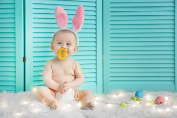 Cute little baby wearing bunny ears sitting on furry rug with garland