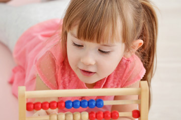 Wall Mural - Cute little girl with abacus at home, closeup