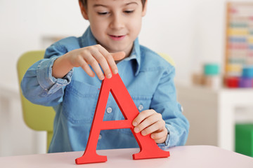 Wall Mural - Cute little boy with letter A at speech therapist office