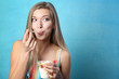 Beautiful young woman eating ice cream on color background