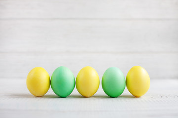 Wall Mural - Yellow and green Easter eggs on a white background. Concept Happy Easter.