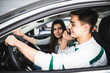 © F8  \ Suport Ukraine - Young woman showing a road in front of the car while the driver using a mobile phone and losing concentration. Dangerous driving.