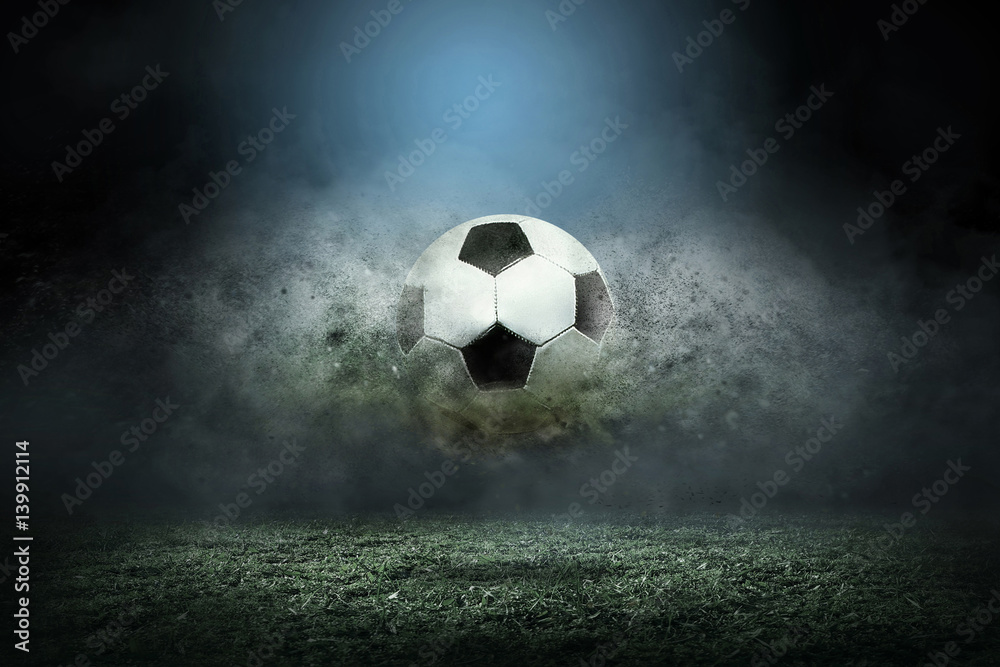 Moving soccer ball around splash drops on the stadium field. - obrazy, fototapety, plakaty 