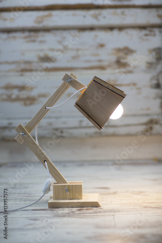 Fotografía A homemade wooden table lamp shines on the floor against a cracked paint vintage