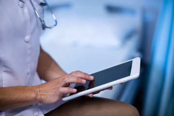 Poster - Mid section of female doctor using digital tablet