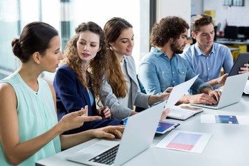 Business team working on laptop and digital tablet in meeting