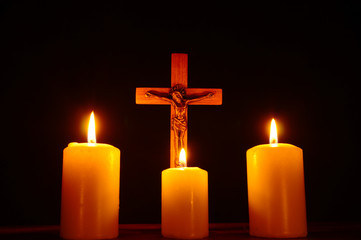 Crucifix and three burning candles in the darkness. Pray to Jesus Christ. 2