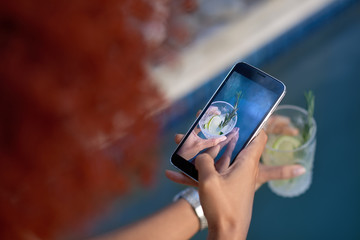 Woman takes photo of cocktail by pool to share on social media 