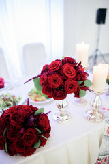 Wall Mural - Little bouquets of red roses lie on white dinner table