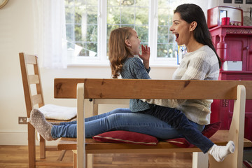 Wall Mural - Daughter Sitting On Mother's Lap At Home And Laughing