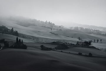 Black and white beautiful summer morning landscape with foggy hills and Tuscany farm houses, travel italian background