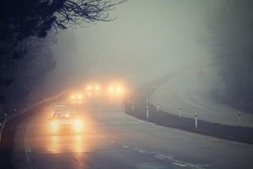 cars in the fog. bad winter weather and dangerous automobile traffic on the road. light vehicles in 