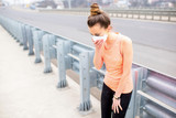 Young sports woman in protective mask resting on the road in the city. Exercising in the city with smog
