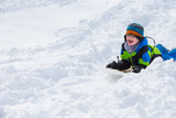 Fototapeta Panele - Boy riding a sled tobogganing in the snow