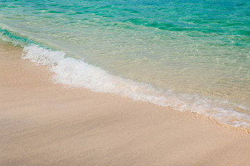 Wall Mural - Peaceful beach background. White sand and turquoise sea water. Ocean coastline of nice sand and calm waves. Tropical vacation concept.