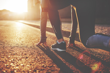 athlete woman in running start pose on the city street. sport tight clothes. bright sunset, blurry b