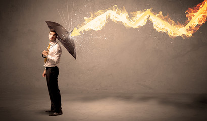 Wall Mural - Business man defending himself from a fire arrow with an umbrella