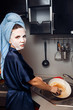 © Parilov - The girl washes the dirty dishes with a frying pan in a nourishing mask on the skin. Mask for rejuvenating and eliminating skin defects. Acne