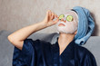 The girl puts and corrects a nutritious mask on a skin with green ripe fresh cucumber. Mask for rejuvenating and eliminating skin defects. Acne, acne.