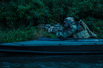 Special forces man with painted face in camouflage uniforms in army kayak. Seeking target, diversionary mission, twilight