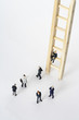 © STOCK4B  - Businessmen figurines standing next to a ladder, one figurine sitting on a rung