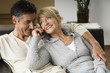 © STOCK4B  - Couple sitting on a sofa while phoning