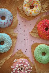 Wall Mural - Tasty colorful donuts on wooden table, close up view