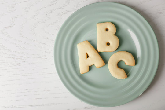 Plate with cookie alphabet on wooden  table