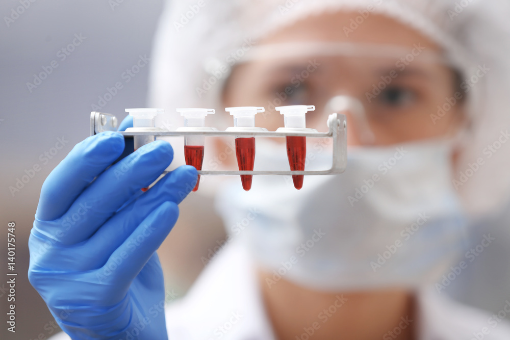 Scientist holding stand with test tubes in laboratory
