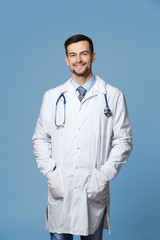 Poster - Handsome young doctor with stethoscope on grey background