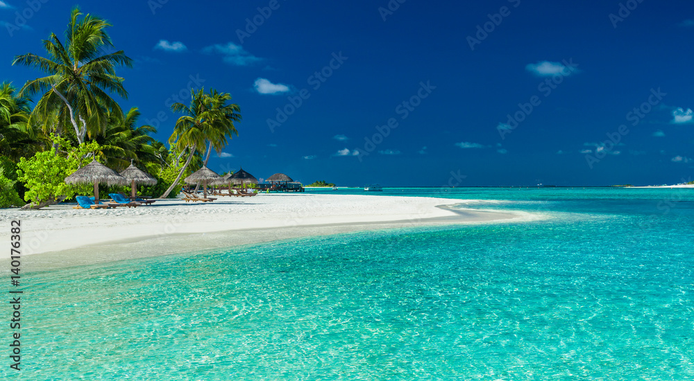 Palm trees and beach umbrelllas over lagoon and white sandy beach, Maldives - obrazy, fototapety, plakaty 