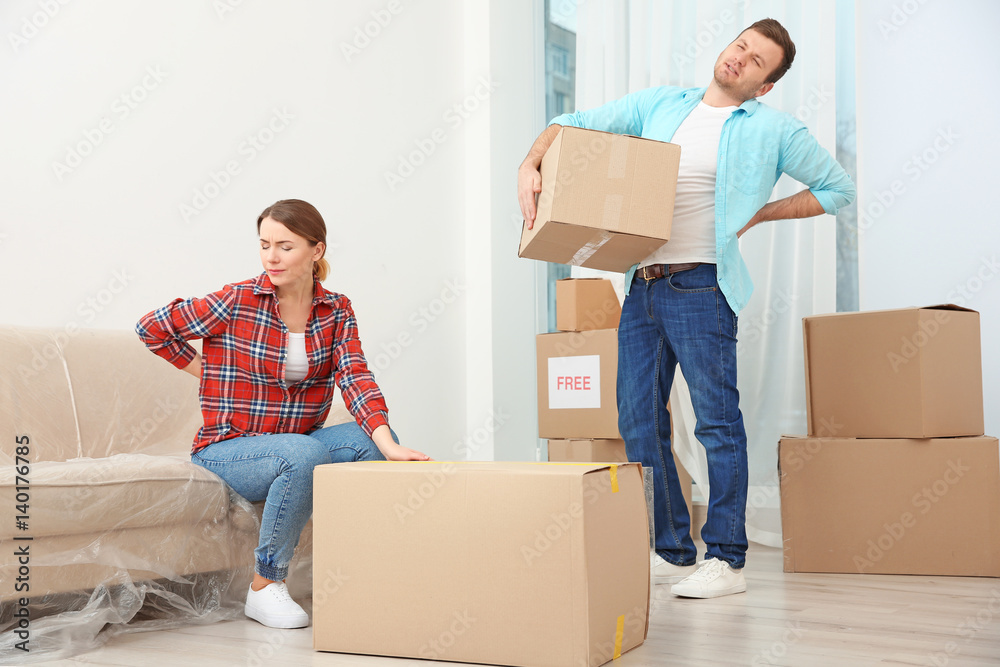 Couple suffering from ache while moving boxes in room