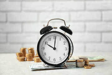 Sticker - Alarm clock and money on white table against brick wall background