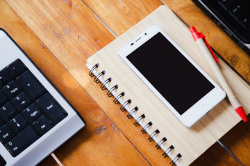 Desktop Mix of office supplies and gadgets . desk with laptop , Smart Phone, glasses , Watch , notebook , tablet, On a wood table.