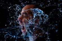 Portrait Of A Man Being Thrown Water In The Face Against A Black Background