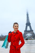 woman in front of Eiffel tower with shopping bag looking aside