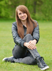beautiful young brunette sitting on fresh green grass