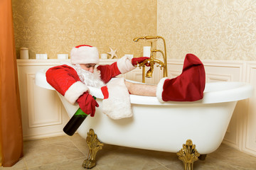 Drunk Santa Claus with bottle sleeping in a bath