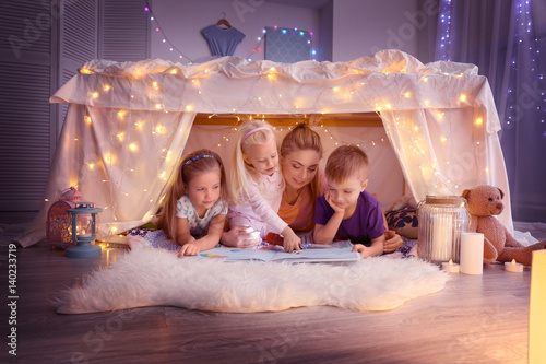 Fotografía Young woman and cute children reading book in hovel at home