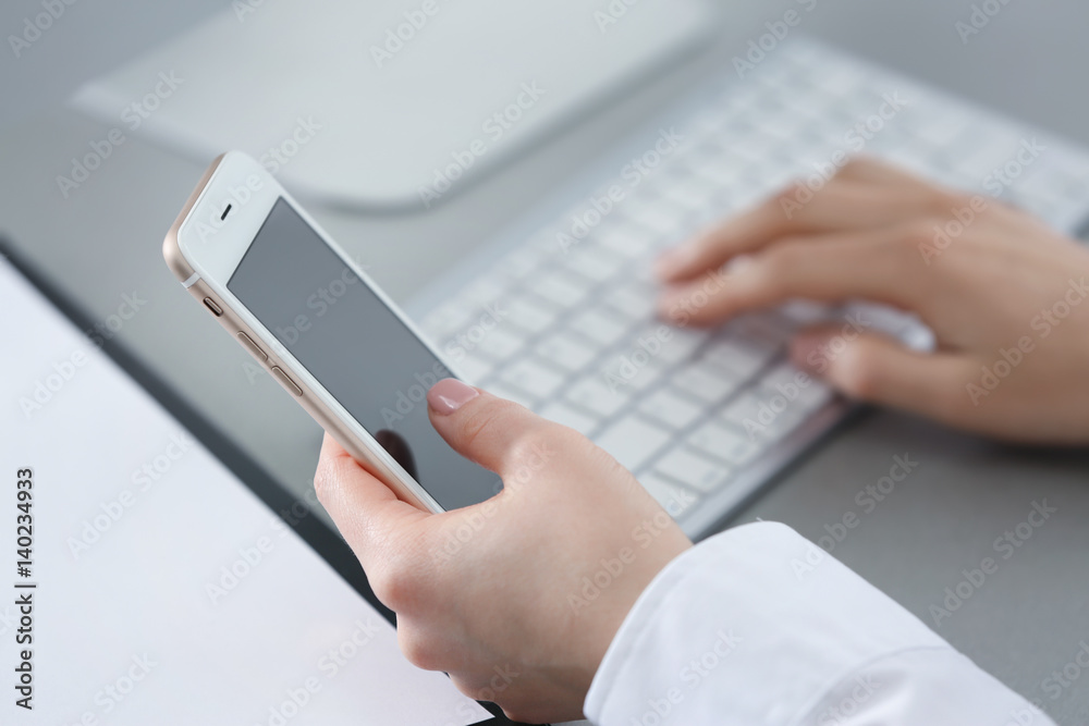 Woman with mobile phone at workplace in office, closeup