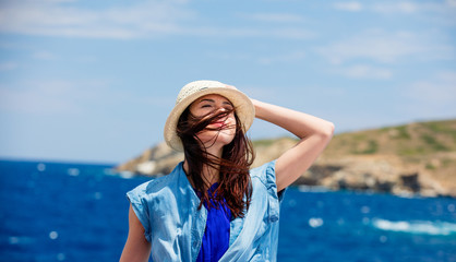 Wall Mural - photo of beautiful young woman on the boat in front of sea and island background in Greece