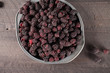 Harvested Boysenberries in silver tin container top view on dark wooden background