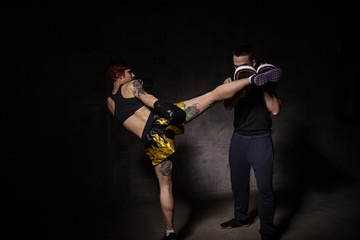 Wall Mural - Woman boxer hitting training mitts held a boxing trainer