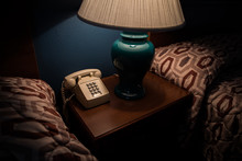 Old Phone And Lamp On A Bedside Table In A Hotel Room